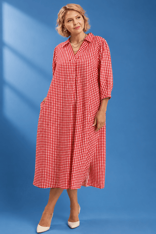 A woman modeling a red and white gingham check midi dress with three-quarter sleeves and a button-down front
