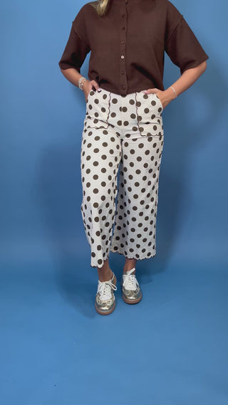 Ivory wide leg pants with brown polka dots, scalloped trim, front pockets, and a cropped fit.