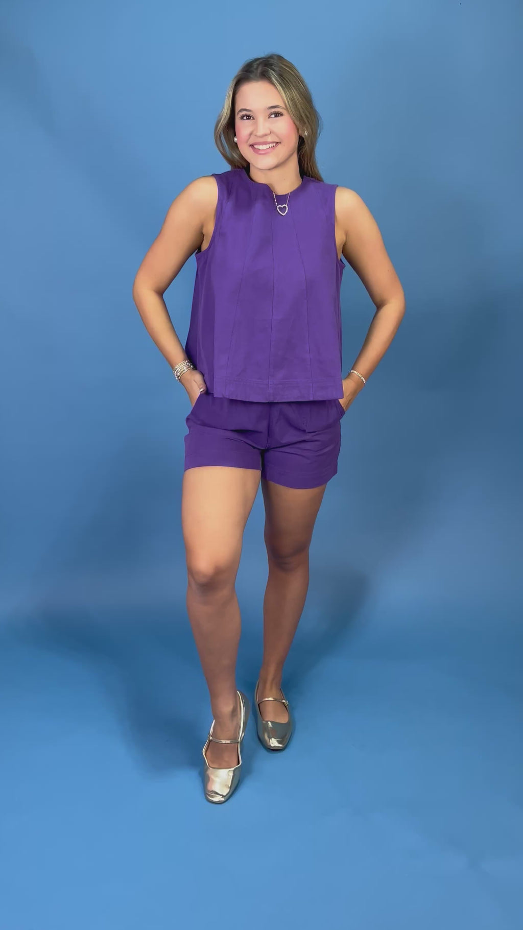 A woman modeling a purple sleeveless crop top and matching purple shorts