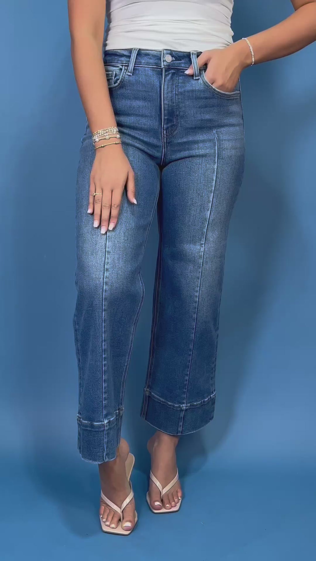 Medium wash high-rise cropped wide leg jeans with front seam detailing, subtle fading, a wide cuffed hem, and small front hem slits.