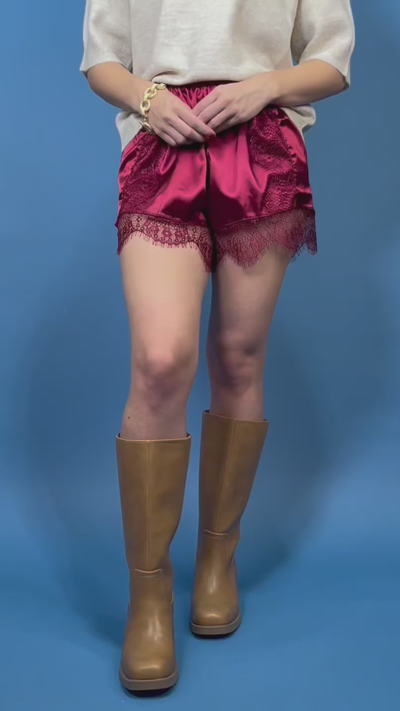 Burgundy satin shorts with delicate lace panels, scalloped lace trim, and a comfortable elastic waist.