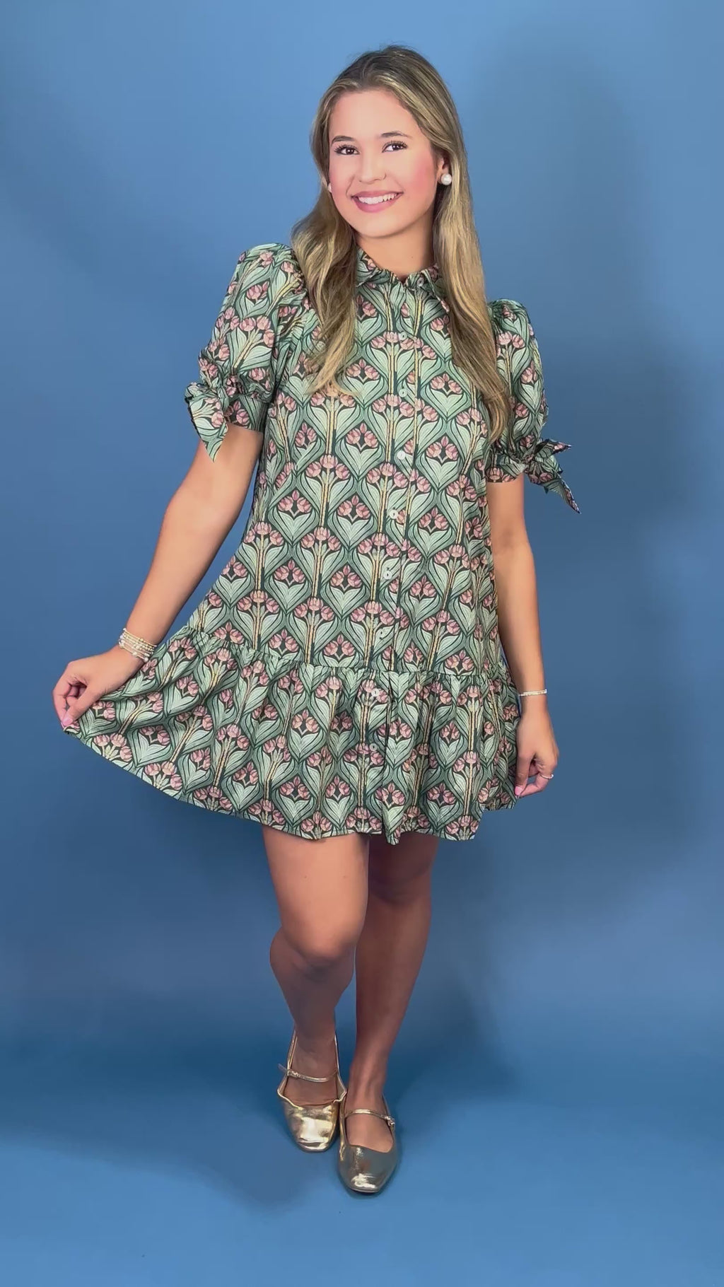 A woman modeling a short puff-sleeve dress with a green, pink, and beige geometric pattern