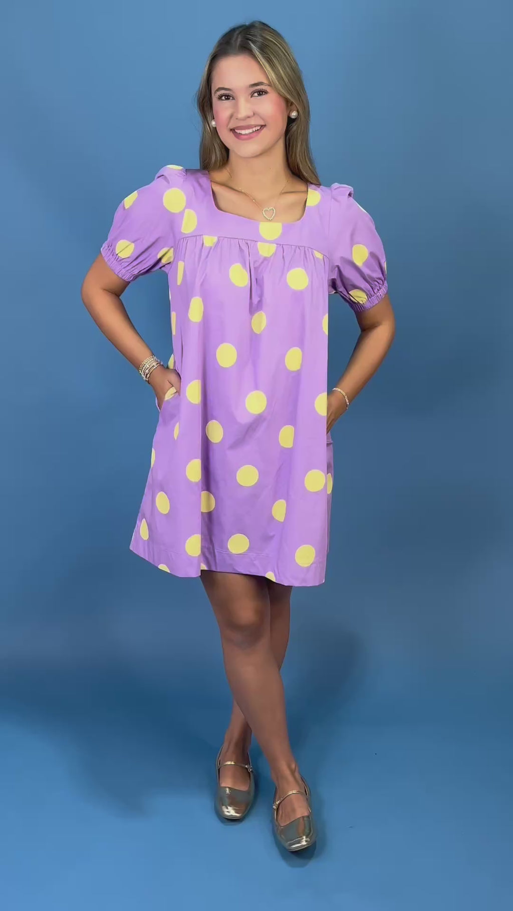 A young woman modeling a lavender purple short-sleeve dress with large yellow polka dots