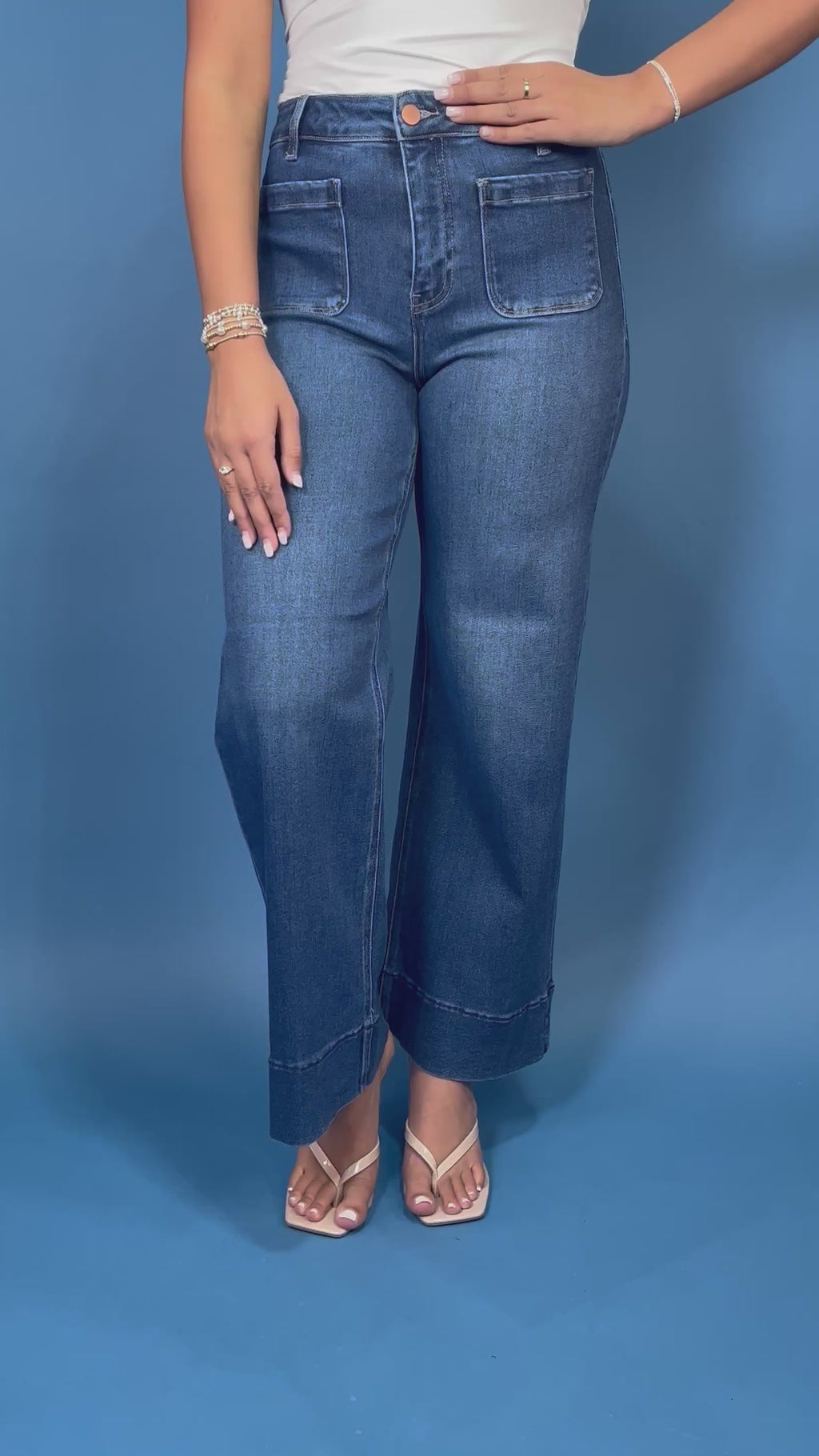 Medium wash high-rise wide leg jeans with front patch pockets, subtle fading, and statement cuffed hems.