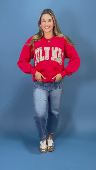 A woman modeling a bright red crewneck sweatshirt with 'LULU MAC' printed in white varsity-style letters