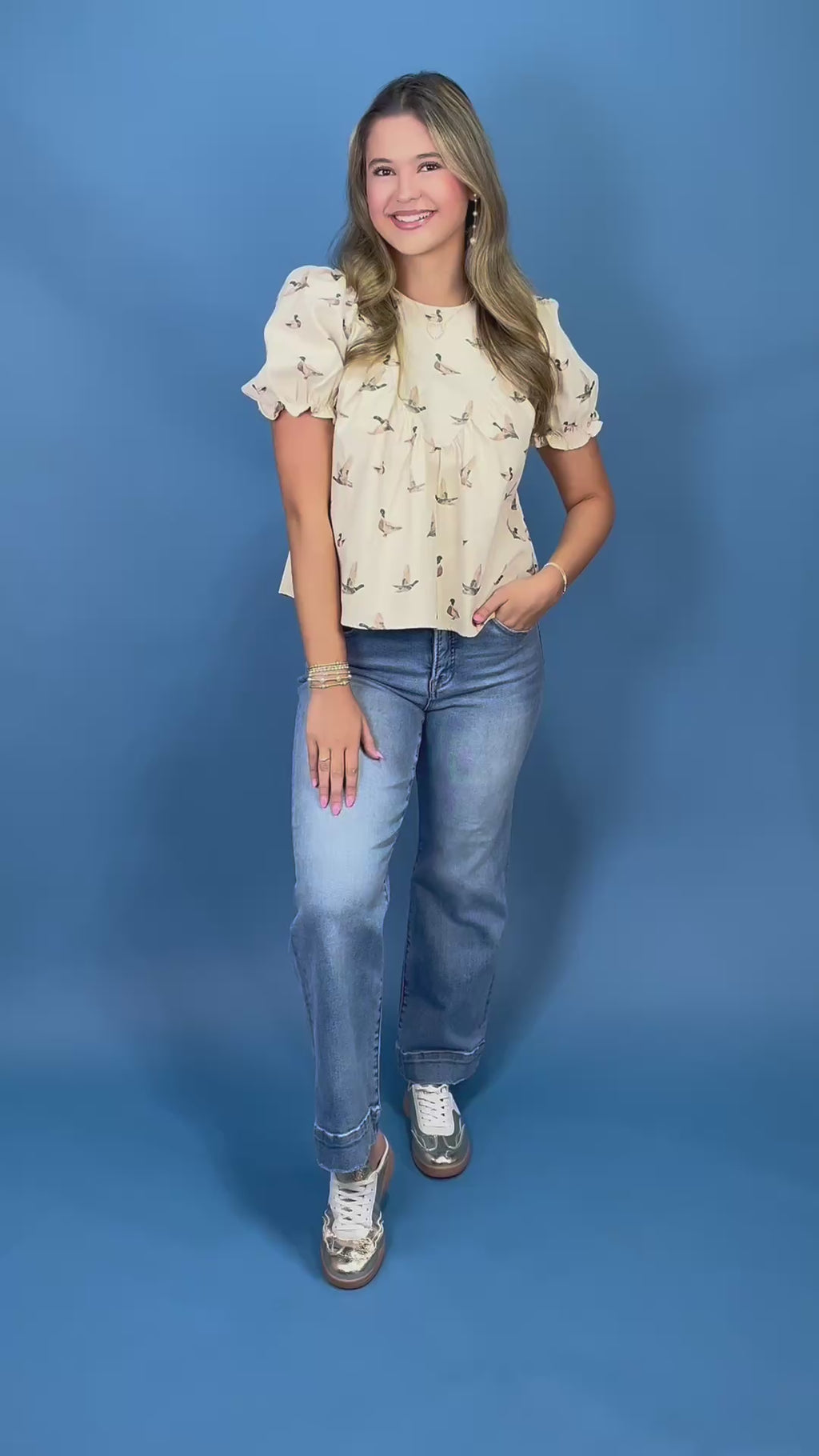 A woman posing in a cream puff-sleeve blouse with a small mallard print 