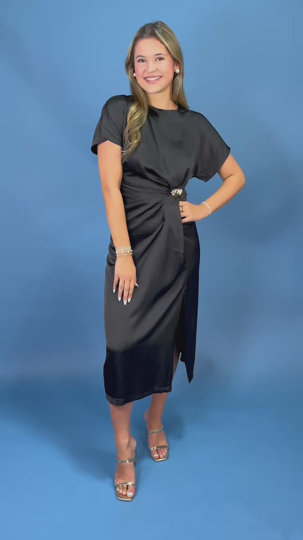 a black midi dress with short flutter sleeves, a draped satin-like finish, and a matching tie belt at the waist.