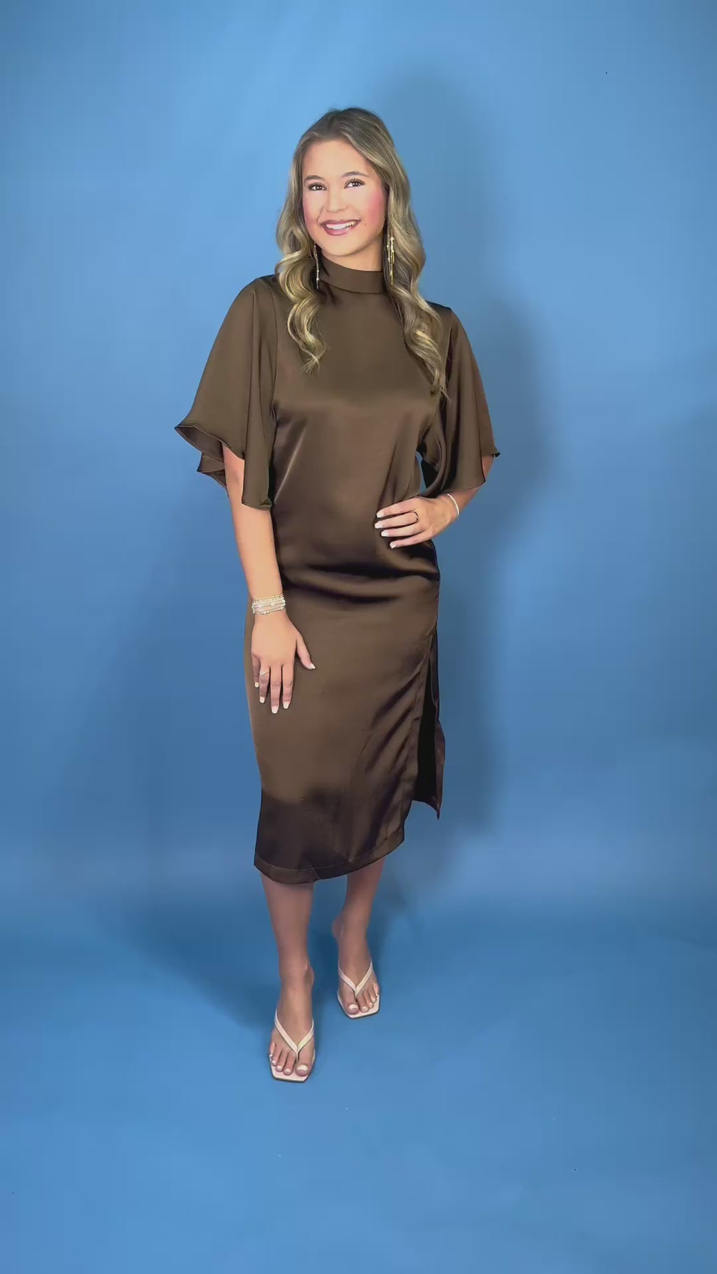 Chocolate brown satin midi dress with mock neckline, flutter sleeves, relaxed silhouette, and side slit detail.