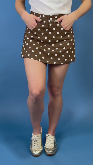 Brown and white polka dot mini skirt featuring a high-rise fit, classic five-pocket styling, button-and-zip closure, and a structured A-line silhouette.