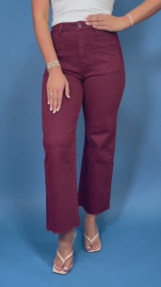 Burgundy high-rise cropped straight leg jeans with front patch pockets and a trendy raw hem.