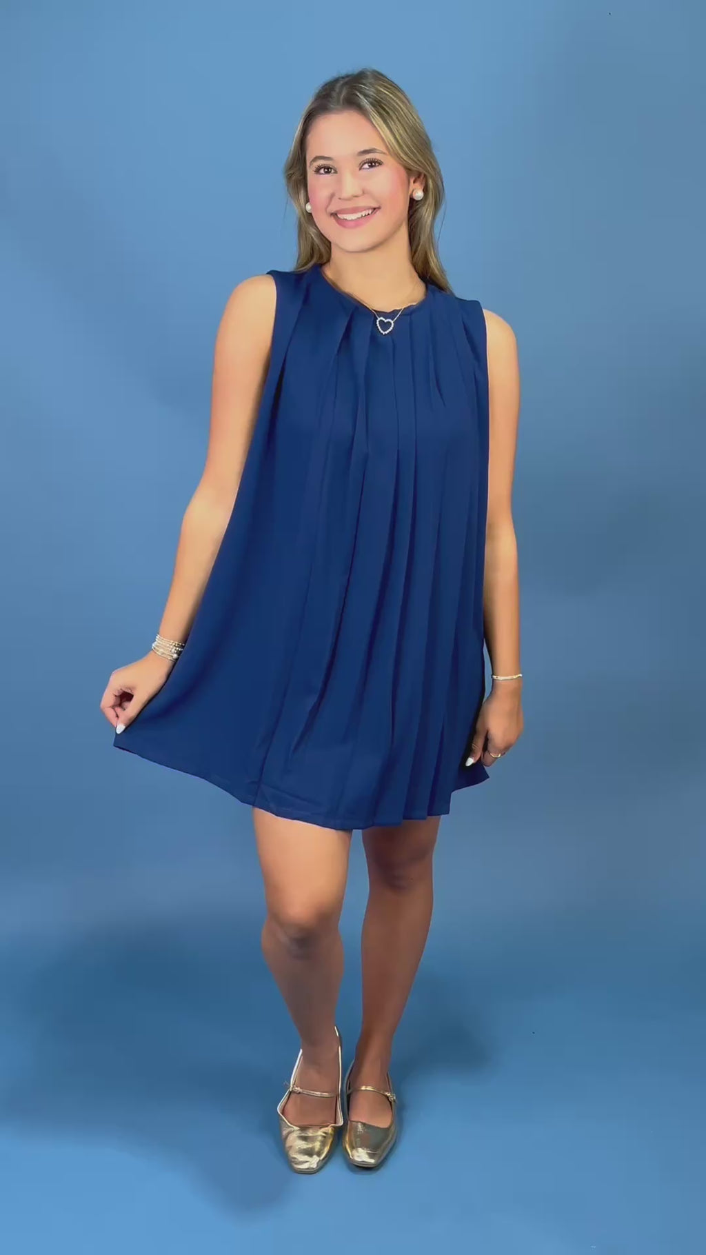 A woman modeling a sleeveless navy blue pleated mini dress