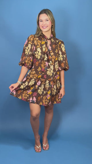 A woman modeling a brown short romper with a colorful floral print