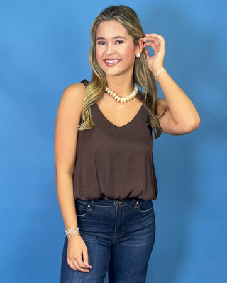 A woman modeling a brown sleeveless top and dark blue wide-leg jeans
