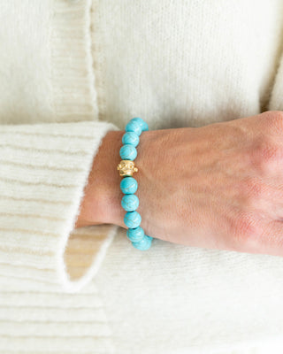 Turquoise beaded bracelet on a wrist with a white background