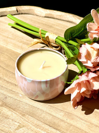 Candle in a decorative container with flowers on a wooden surface