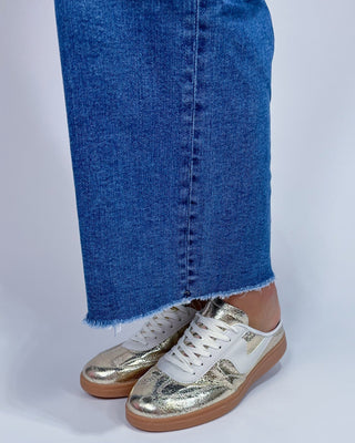 A person wearing medium-wash blue denim jeans with a straight-to-wide leg fit,