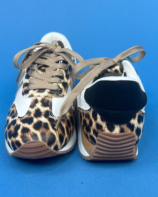 A pair of low-top sneakers shown from the back, featuring a leopard print pattern in brown, black, and beige, with white si