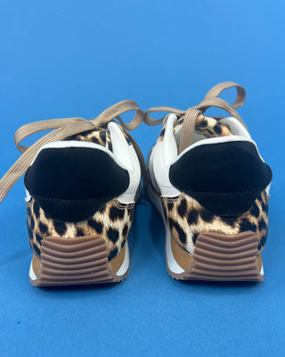 A pair of low-top sneakers shown from the back, featuring a leopard print pattern on the sides, white panels, black heel ta