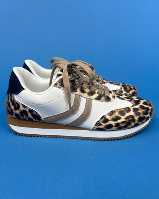 A pair of low-top sneakers featuring a white leather upper with leopard print overlays, beige laces, and a brown and white s