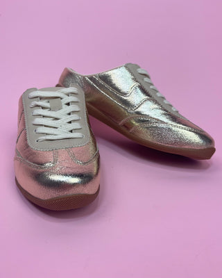 Metallic gold lace-up sneakers with a shiny textured finish, cream accents, white laces, and gum rubber soles. Stylish low-to