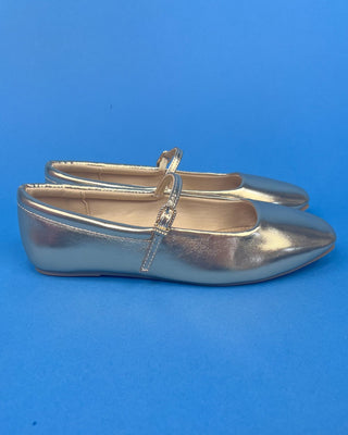 A pair of metallic silver ballet flats with pointed toes and a small buckle strap across the instep, shown against a solid b