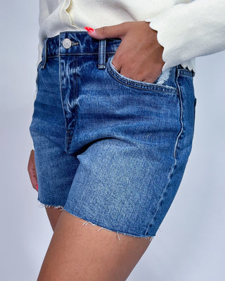 A model wearing high-waisted, frayed-hem blue denim shorts