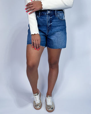 A model wearing high-waisted, frayed-hem blue denim shorts