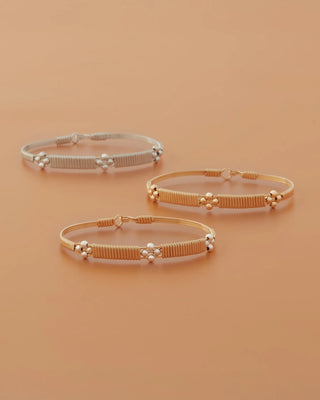 Three gold bracelets on a beige background