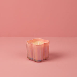 Pink ribbed candle holder with a candle on a pink background