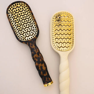 Two paddle brushes with tortoiseshell and cream handles on a light background