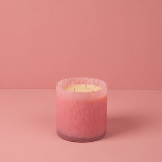 Pink candle in a glass container on a pink background